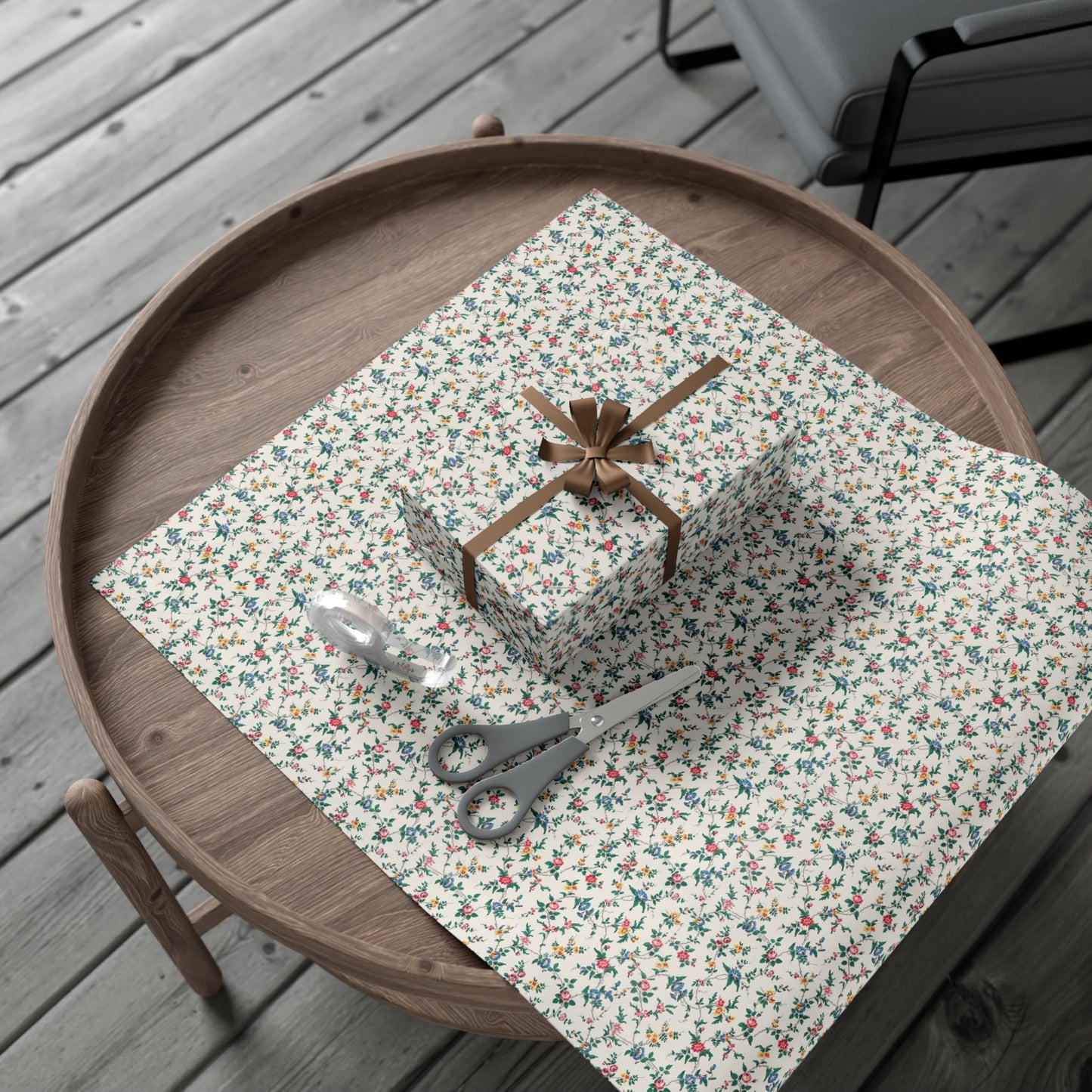 Floral-patterned tablecloth with a gift and scissors on a wooden tray