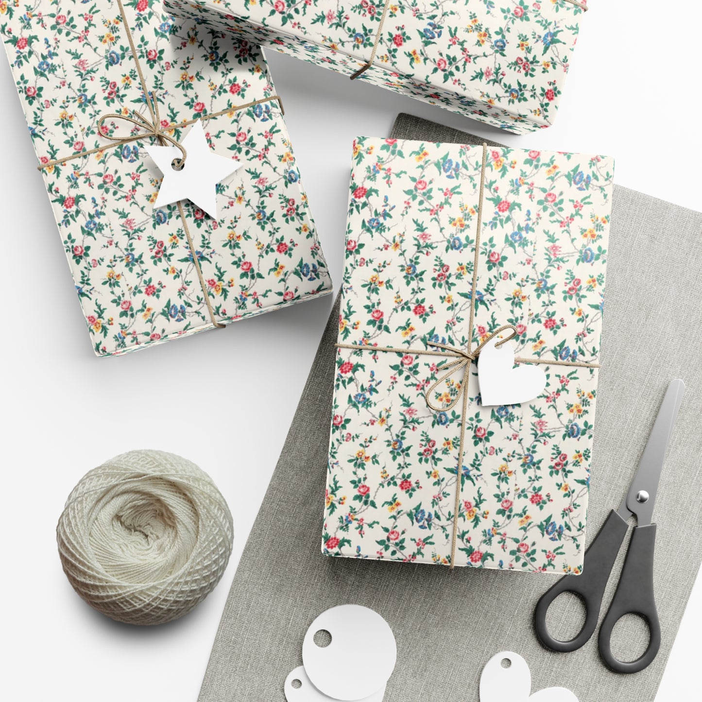 Floral-patterned gift boxes with string, scissors, and yarn on a white surface