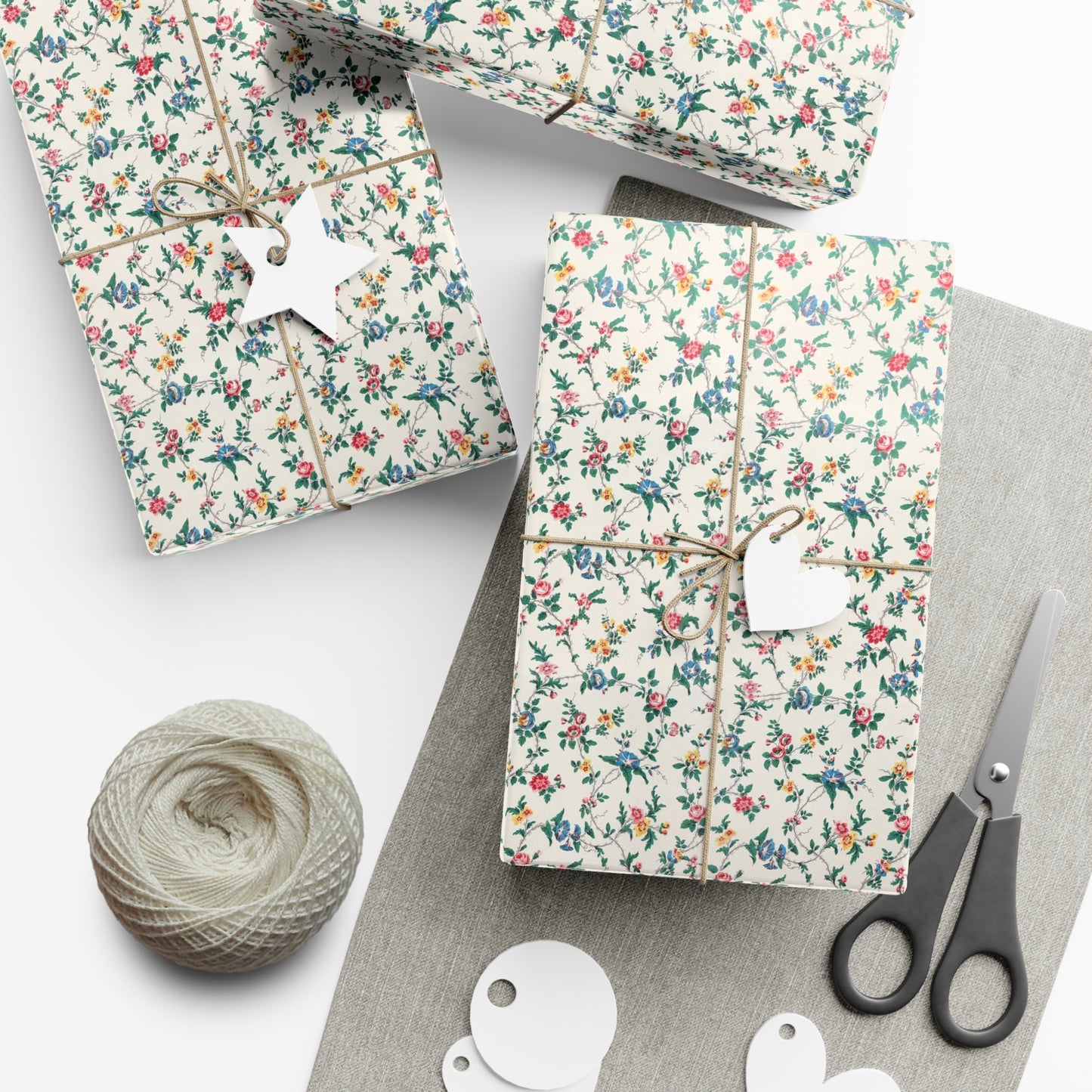 Floral-patterned gift boxes with string, scissors, and yarn on a white surface