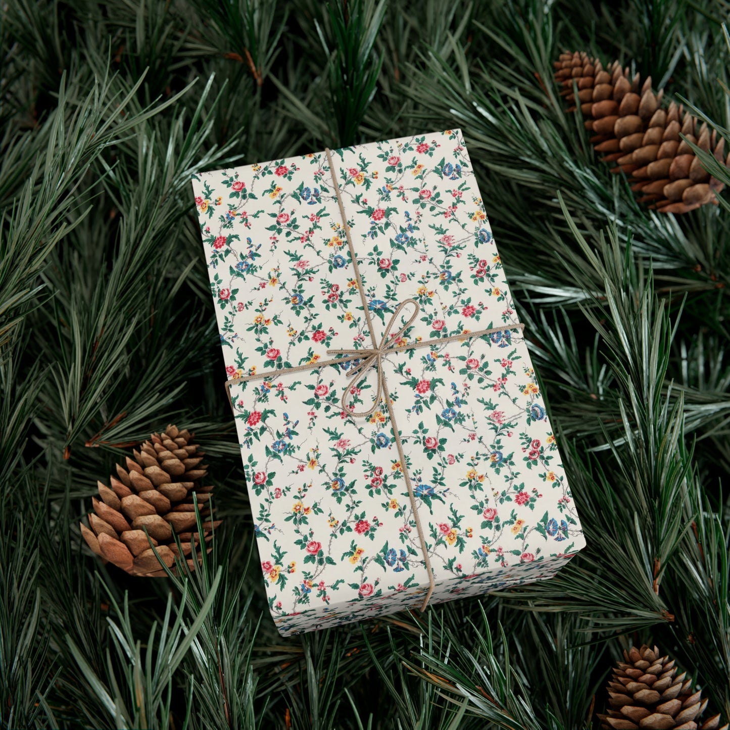 Gift box with floral wrapping paper on a bed of pine needles and pine cones