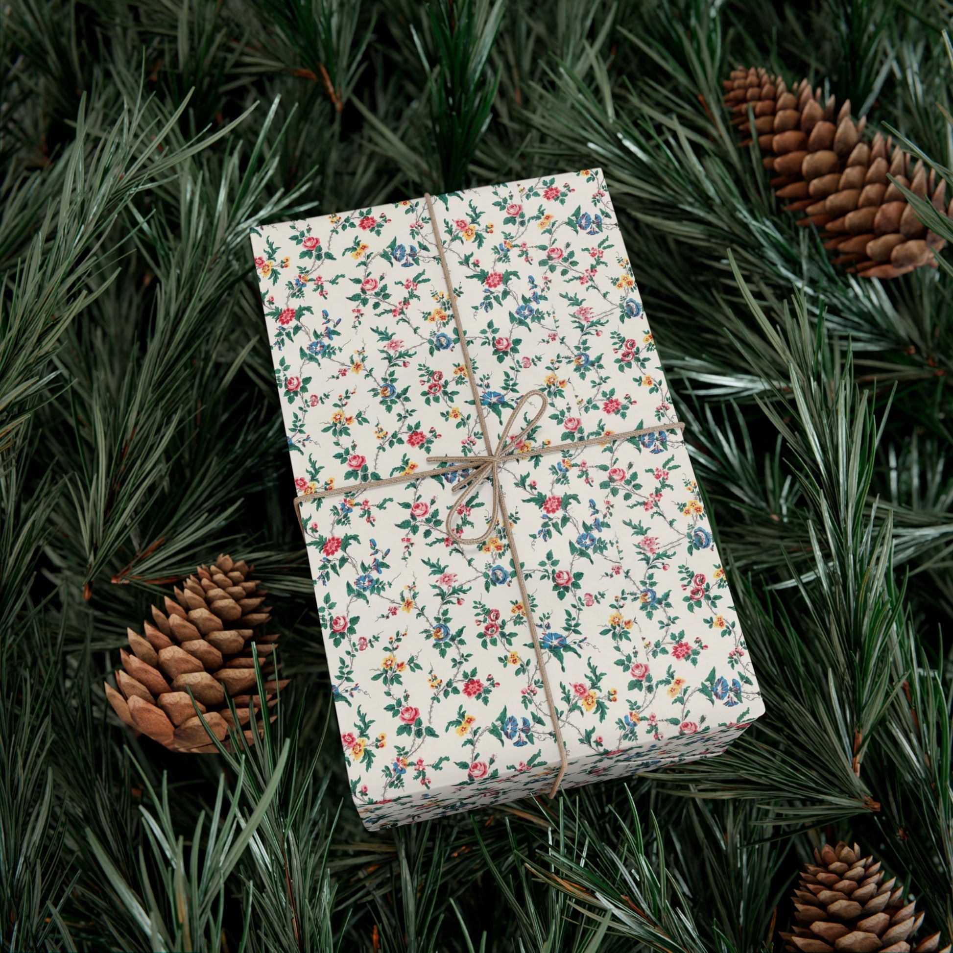 Gift box with floral wrapping paper on a bed of pine needles and pine cones